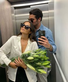 a man and woman taking a selfie in an elevator with flowers on the floor