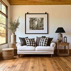 a living room with wood flooring and white couch in front of a window on the wall