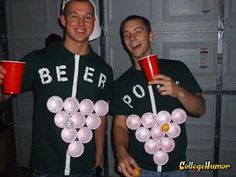 two men in green shirts holding red cups and white balloons while standing next to each other