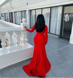 a woman in a red dress standing on a balcony