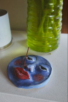 a blue and red object sitting on top of a table next to a green bottle