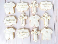 cookies decorated to look like baby clothes with names and cross on them, all in white icing