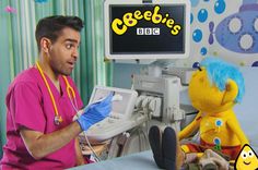 a man in scrubs sitting next to a stuffed animal on a hospital bed with an iv machine