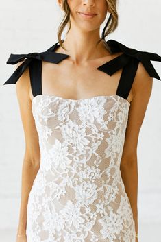 a woman wearing a white dress with black bows