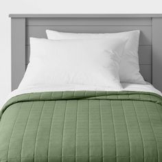 a bed with two pillows on top of it and a green comforter in the middle