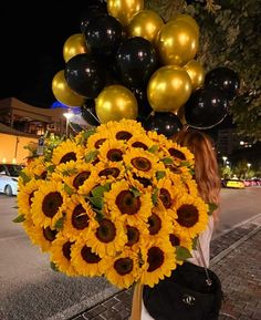 a woman holding a large bouquet of sunflowers