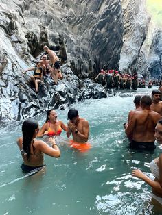 some people are in the water and one is wearing a bathing suit while others watch