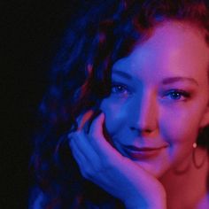 a close up of a person with long curly hair and blue light in the background