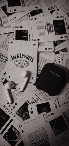 a pile of jack daniels playing cards and earbuds on top of newspaper pages