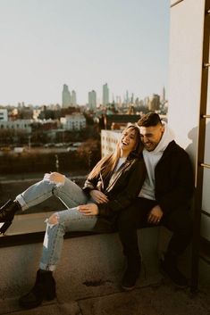 a man and woman sitting next to each other on top of a building