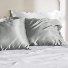 two pillows on top of a bed with white sheets