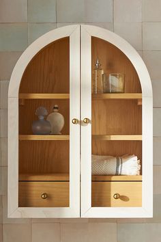 an arched wooden cabinet with glass doors