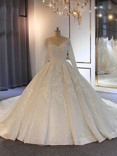 a white wedding dress is on display in front of a mirror and chandelier