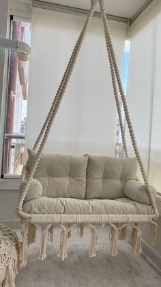 a white couch hanging from a rope in front of a window