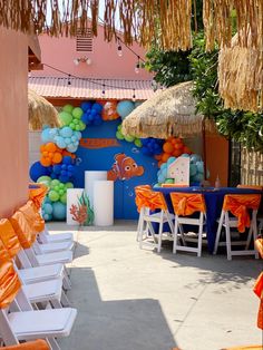 an orange and blue birthday party is set up with chairs, umbrellas and decorations