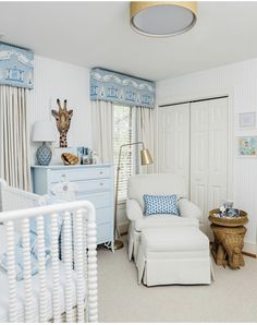 a baby's room with a giraffe head on the wall and white furniture