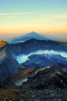 the view from top of a mountain looking down on a lake and mountains in the distance