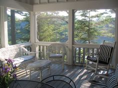 a screened porch with wicker furniture and large windows