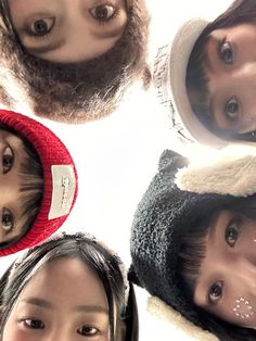 four young women are standing in a circle with their faces painted white and wearing winter hats