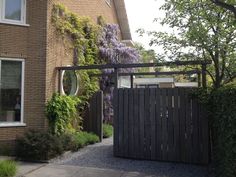 an entrance to a house with purple wisters growing on the side of it