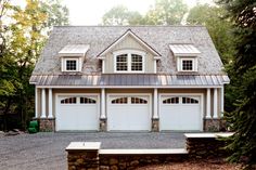 a house with two garages in the front and one on the side, surrounded by trees