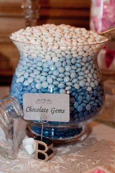 a glass vase filled with lots of blue and white candies on top of a table