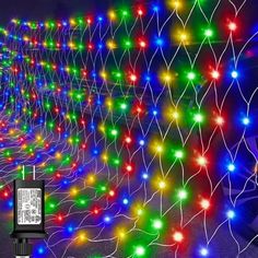 an array of multicolored christmas lights on a wall with a cell phone in the foreground