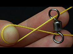 a person holding a yellow string with a small metal object on it's end