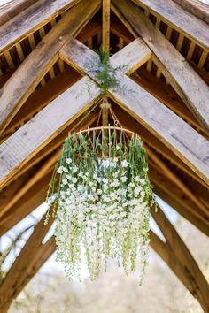 a chandelier with flowers hanging from it's ceiling in a wooden structure