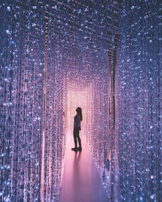 a woman is standing in the middle of a tunnel of lights