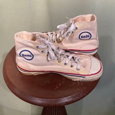 "This is a vintage pair of kid's Keds high top sneakers. They date from the 1950s or so. Deadstock, soles show no signs of wear. Stock number 3405TC. Made of off-white canvas with rubber soles & toes. They are marked a Youth size 2-1/2. The toes & front of the toe's sole has a ribbed, rubber cap. The eyelets have a strip of vinyl reinforcement. There is a red & a blue stripe running all around the top edges of the soles & a blue \"Keds\" logo square on the back of the heels. The inner ankle has Vintage High-top Sneakers With Gum Sole For Streetwear, Vintage High-top Sneakers With Vulcanized Sole, Vintage Mid-top Sneakers With Rubber Sole, Retro Mid-top High-top Sneakers With Gum Sole, Retro Mid-top Sneakers, Vintage Sneakers With Gum Sole And Round Toe, Vintage Sneakers With Gum Sole, Vintage High-top Lace-up Sneakers With Vulcanized Sole, Retro Lace-up High-top Sneakers