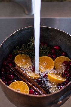 oranges and cranberries are being cooked in a pan with water on the stove