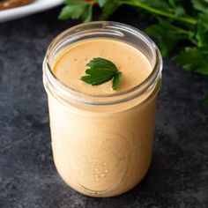 a glass jar filled with liquid sitting on top of a table next to green leaves