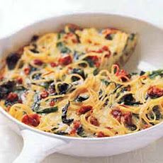 a casserole dish with spinach, cheese and tomatoes in it on a white table