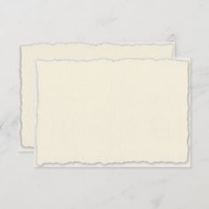 two pieces of paper with torn edges sitting on top of a white tablecloth background