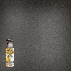 a bottle of spray paint sitting on top of a black countertop next to a white wall