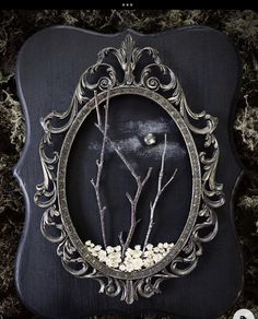 an ornate frame with flowers and branches in the center on mossy ground, framed by metal filigrees