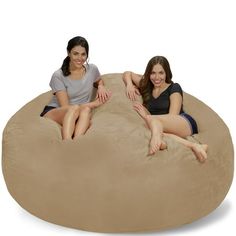 two women sitting on a large bean bag chair in the shape of a boat and smiling at the camera