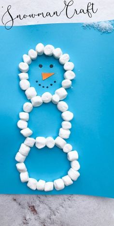 a snowman craft made out of marshmallows on a blue background with text overlay