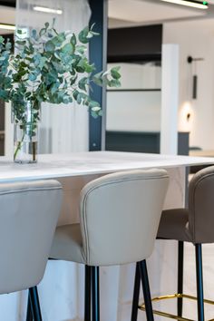 three white chairs sitting at a table with flowers in a vase