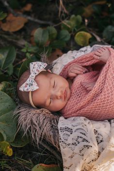 a newborn baby is wrapped in a pink blanket and laying on the ground with her eyes closed