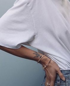 a woman with tattoos on her arm wearing jeans and a white t - shirt is posing for the camera