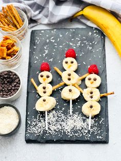 some food is on a black plate with bananas and strawberries in the shape of snowmen