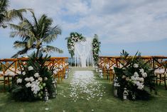 an outdoor ceremony setup with white flowers and greenery on the grass, surrounded by palm trees