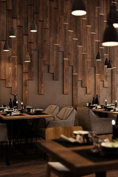 an empty restaurant with wood paneling and modern lighting fixtures on the wall, along with chairs and tables