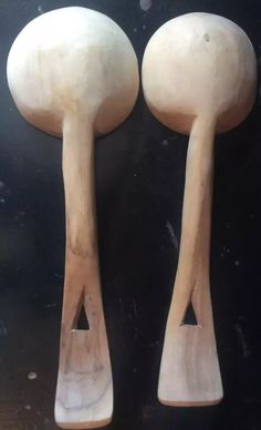 two large wooden spoons sitting next to each other on top of a black surface