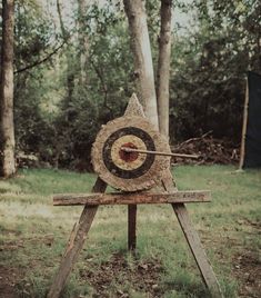 an arrow stuck in the center of a wooden target on top of a piece of wood