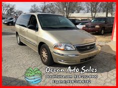 a gold van parked in a parking lot next to other cars and trucks with the ocean auto sales logo on it