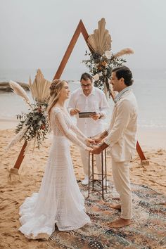 a bride and groom exchanging vows on the beach