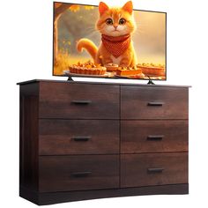 an orange cat sitting on top of a dresser next to a tv screen that is turned on